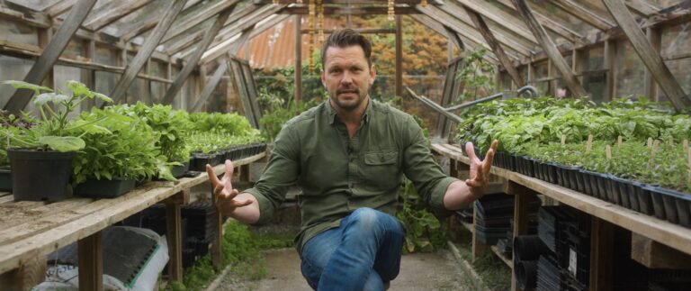 An image of TV presenter Jimmy Doherty sitting in a glass house ion Heligan as he speaks to camera.