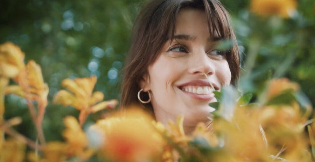 A FatFace model smiling among yellow flowers