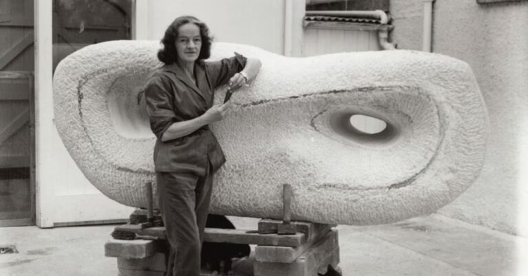 A vintage photograph of Barbara Hepworth leaning on a giant sculpture in St Ives.