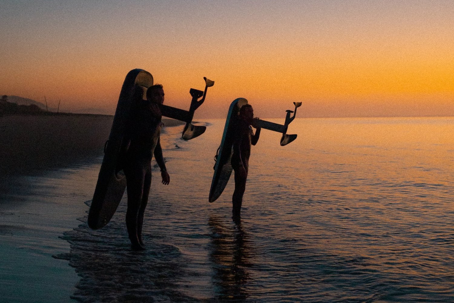 A colour graded image of The Turner Twins with Flite Boards over their shoulder looking across a  sunset.