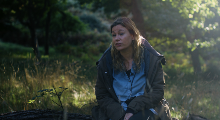 An image of a social prescriber sitting on a log for an interview.