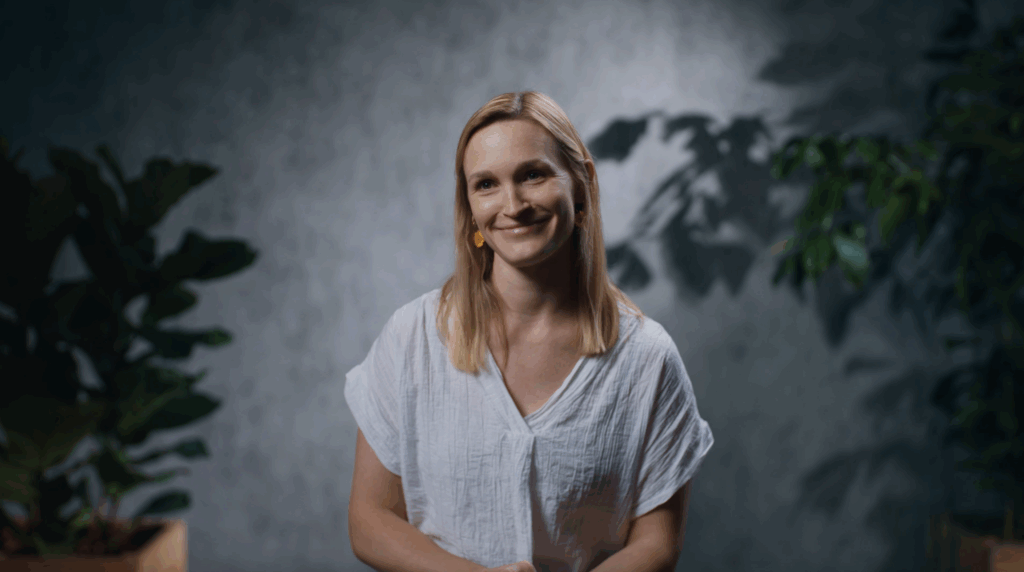 An image of Sammy Hansen - sustainability lead at Pepsi co - smiling into the camera infront of a grey backdrop from a recent corporate video production in London with Here Now Films.