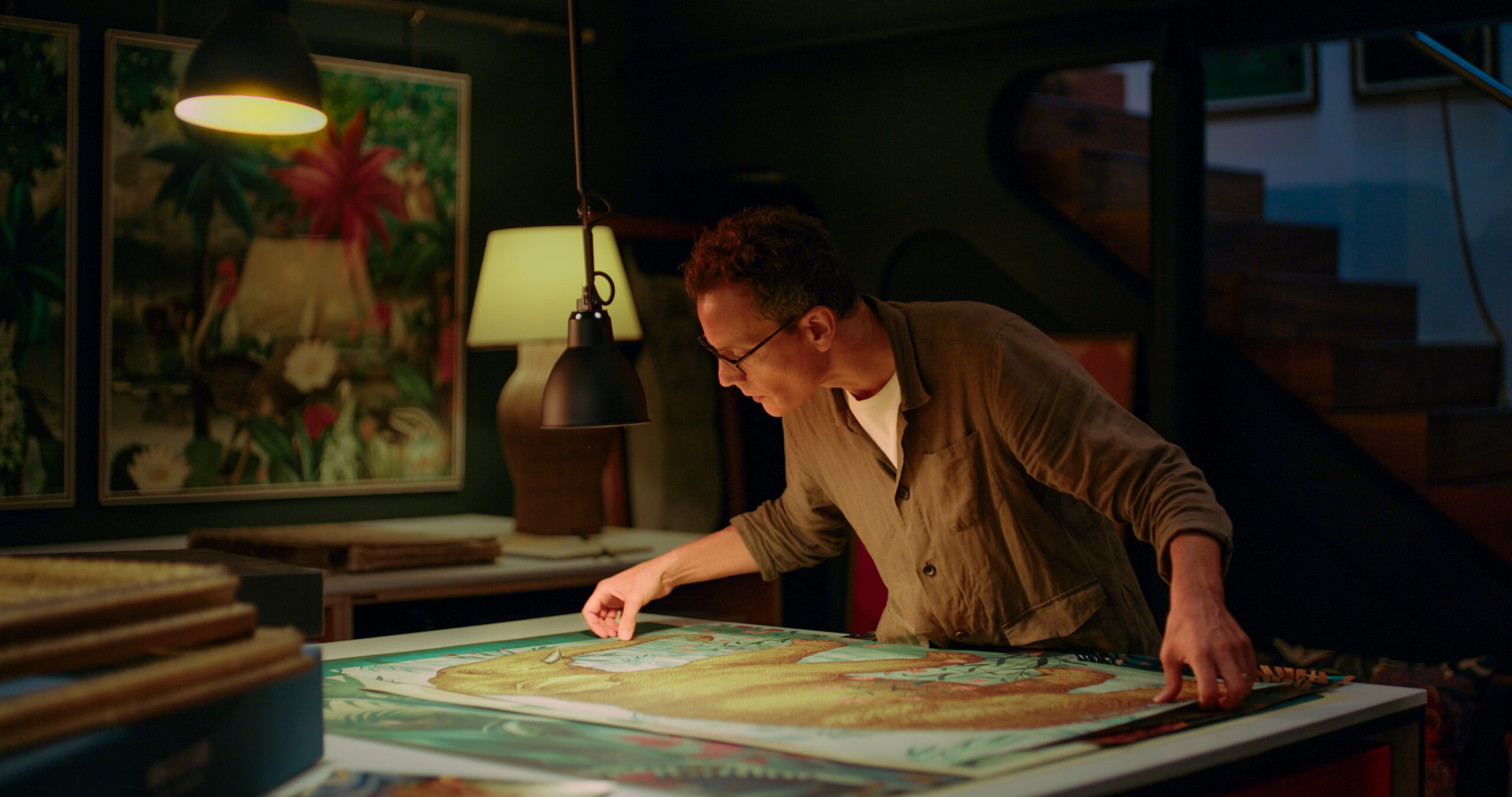 An image of Adam Ellis - print maker and designer - looking over his designs in a studio for a video production in London.