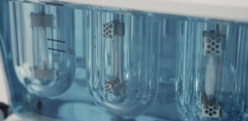 An image of scientific instruments from the cali lilly lab, a blue fluid moves between glass jars.