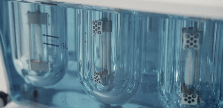 An image of scientific instruments from the cali lilly lab, a blue fluid moves between glass jars.