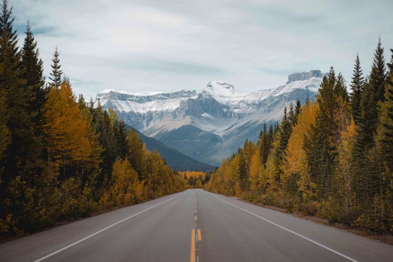 An image of a canadian road in Spring with mountains in the background.