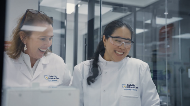 Calla Lilly Founder in a lab coat looking at her medical device.