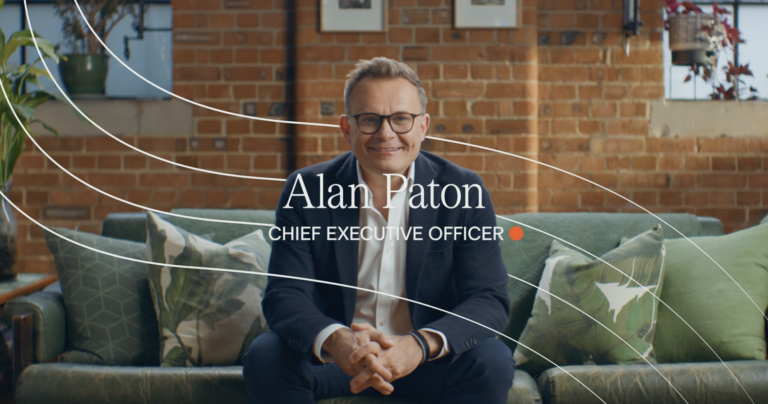 An Image of Alan Paton - Chief Executive Officer at Beyond AI - sitting on a green sofa looking at the lens of the camera.