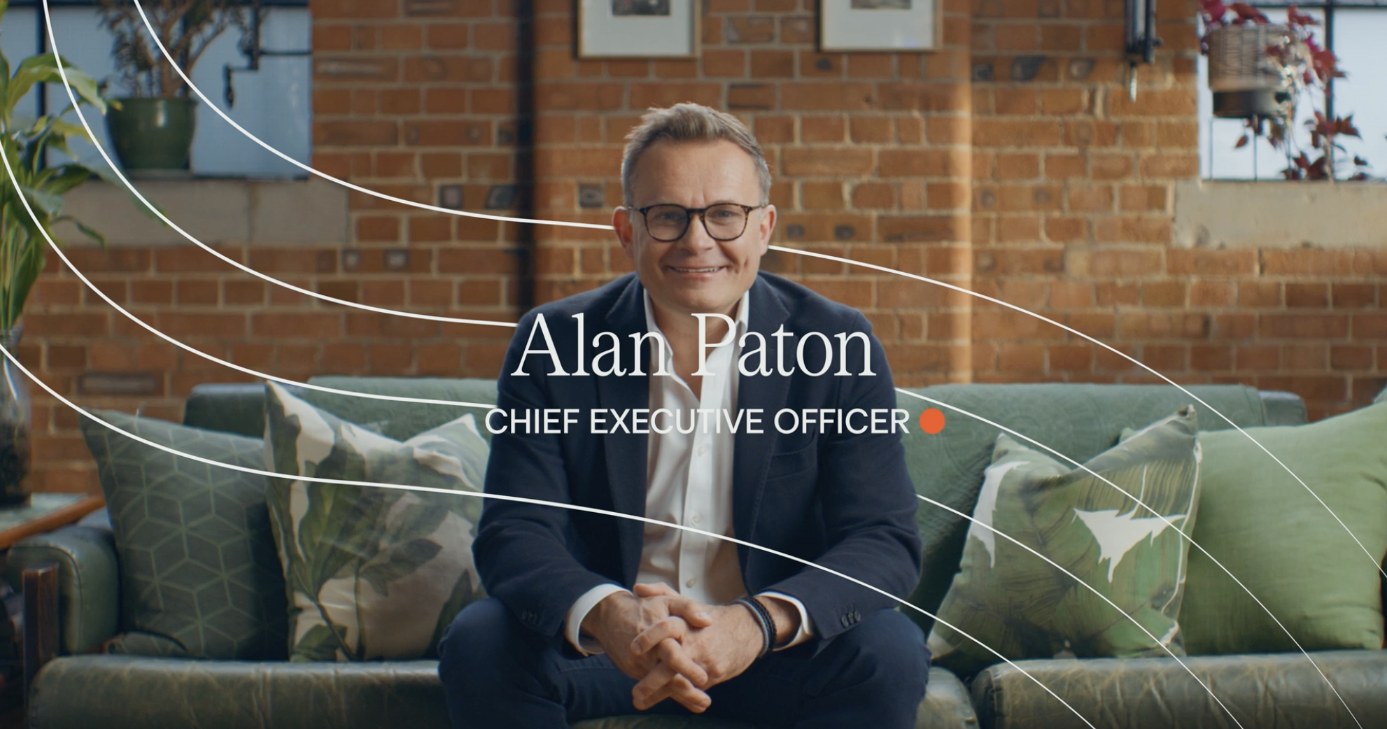 An Image of Alan Paton - Chief Executive Officer at Beyond AI - sitting on a green sofa looking at the lens of the camera.