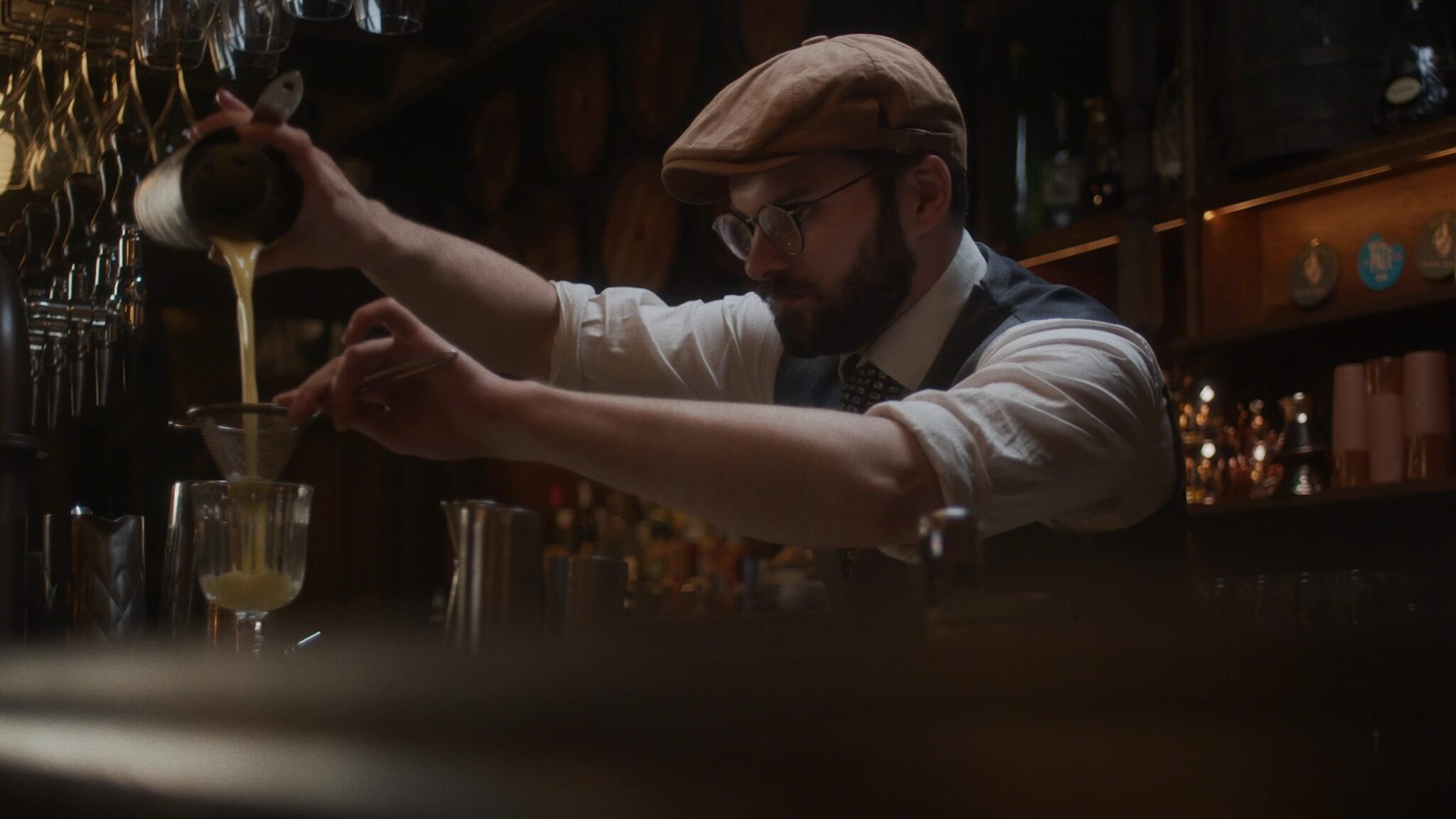 A bartender making a cocktail behind the bar, from Toast’s customer story at Mr Fogg’s City Tavern in London
