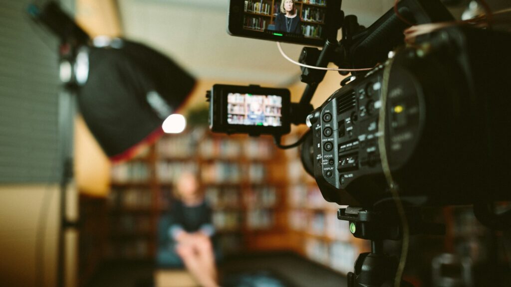 A cinema camera and monitor framing an interview in a library