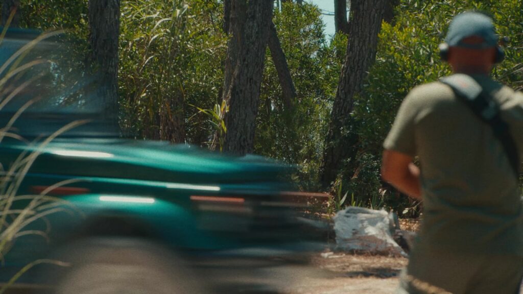 A car speeding past our sound recordist, headphones on, on a forest track on the Cohere shoot