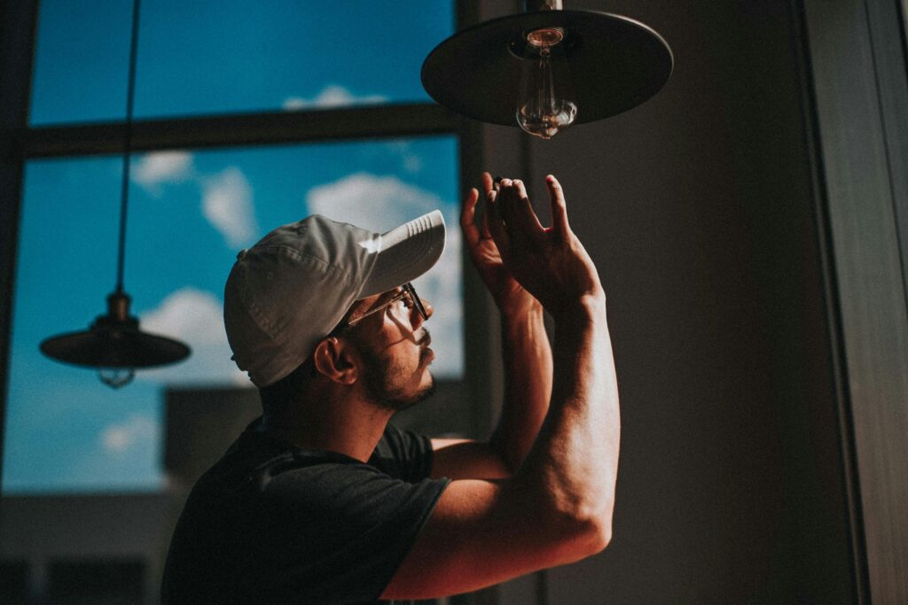 A spark fitting a bulb into a pendant lamp on set